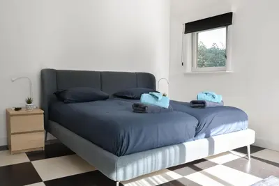 a bedroom with a bed with blue sheets and a window at Spacious Comfort Villa Vera with hottub in Zeewolde
