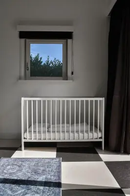 a white crib in a room with a window at Spacious Comfort Villa Vera with hottub in Zeewolde