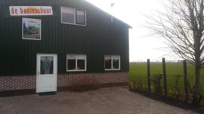 a green building with a white door and a fence at boerenskuur De Bedstee groen in Assendelft