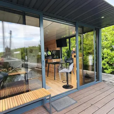 a house with glass doors and a bench on a deck at Modern, brand new houseboat near Amsterdam in Monnickendam