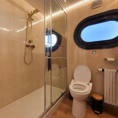 a bathroom with a toilet and a shower with a window at Modern, brand new houseboat near Amsterdam in Monnickendam