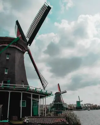 two windmills on the water with a cloudy at Modern, brand new houseboat near Amsterdam in Monnickendam