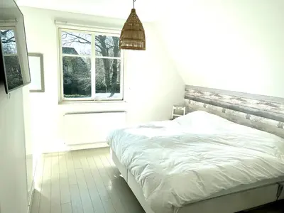 a bedroom with a white bed and a window at Villa Boho Beach in Bergen