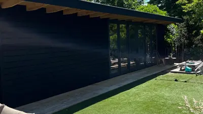 a black shed with a deck and grass at Villa Boho Beach in Bergen