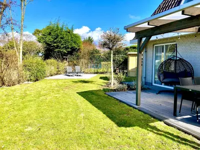a patio with a table and a swing on a deck at Maralong Noordwijk in Noordwijk