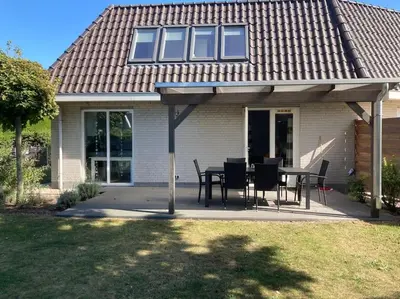 a house with a patio with a table and chairs at Maralong Noordwijk in Noordwijk
