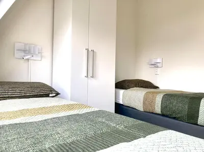 a bedroom with two beds and a cupboard with at Maralong Noordwijk in Noordwijk