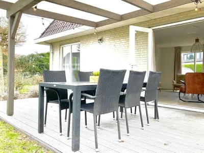 a dining table and chairs on a deck at Maralong Noordwijk in Noordwijk