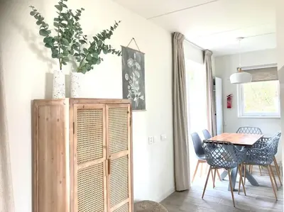 a dining room with a table and a wooden cabinet at Maralong Noordwijk in Noordwijk