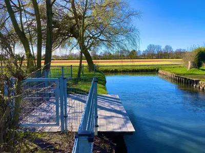 a bridge over a river with a field of tulips at Maralong Noordwijk in Noordwijk