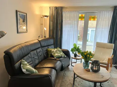 a living room with a leather couch and a table at Vakantiewoning aan Zee - 150m van het Strand in Egmond aan Zee