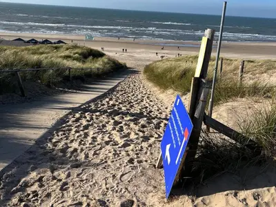 a blue sign in the sand on a beach at Vakantiewoning aan Zee - 150m van het Strand in Egmond aan Zee