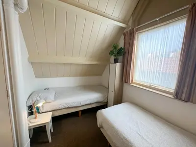 a small room with two beds and a window at Vakantiewoning aan Zee - 150m van het Strand in Egmond aan Zee