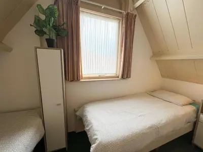 a small bedroom with two beds and a window at Vakantiewoning aan Zee - 150m van het Strand in Egmond aan Zee