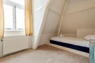a small bedroom with a bed and a window at Zandvoort Zenith - Beautiful Apartment in Zandvoort