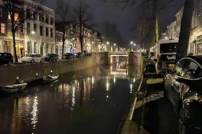 a canal in a city at night with cars parked at Apartment City Center Gouda in Gouda