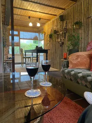 two glasses of wine sitting on a glass table in a living room at Casa Calida in Warmenhuizen