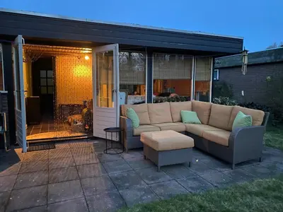 a patio with a couch and a glass door at Casa Calida in Warmenhuizen