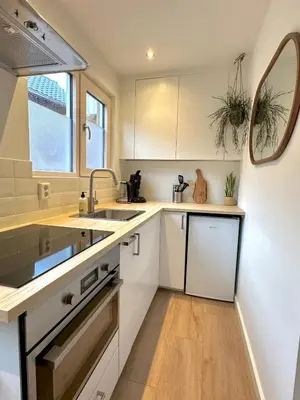 a kitchen with white cabinets and a sink and a mirror at Wellness at Sea in Egmond aan Zee