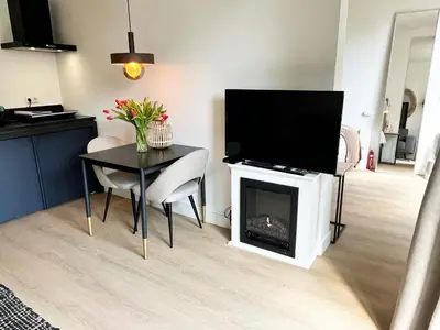 a living room with a table and a television on a fireplace at The East Wing Bloemendaal in Bloemendaal