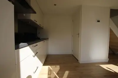 a kitchen with white cabinets and a wooden floor at Have a nice stay! - Zomerhuis Benita's met parkeer plaats in Noordwijk aan Zee