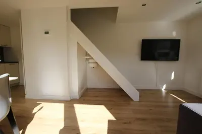 a living room with a staircase and a tv at Have a nice stay! - Zomerhuis Benita's met parkeer plaats in Noordwijk aan Zee