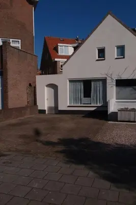 a large white house and a brick building at Have a nice stay! - Zomerhuis Toda Cambia dicht bij strand in Noordwijk aan Zee