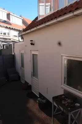a white building with a window and a table next to it at Have a nice stay! - Zomerhuis Toda Cambia dicht bij strand in Noordwijk aan Zee