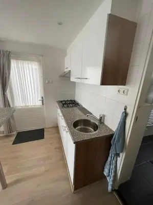 a small kitchen with a sink and a stove at Have a nice stay! - Zomerhuis Toda Cambia dicht bij strand in Noordwijk aan Zee