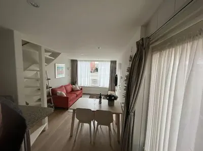 a living room with a table and chairs and a red couch at Have a nice stay! - Zomerhuis Toda Cambia dicht bij strand in Noordwijk aan Zee