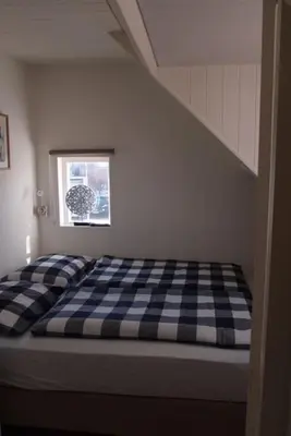 a bed in a room with a checkered mattress at Have a nice stay! - Zomerhuis Toda Cambia dicht bij strand in Noordwijk aan Zee