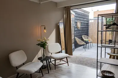 a room with chairs and a table and a balcony at La Siesta Noordwijk Zee in Noordwijk