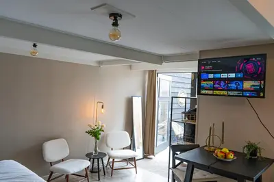 a living room with a table and a tv on the wall at La Siesta Noordwijk Zee in Noordwijk