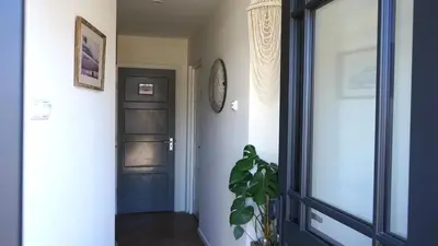 a hallway with a black door and a plant at Maun Apartment in Zandvoort