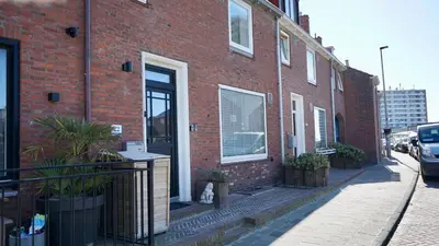 a brick building with a dog sitting outside of it at Maun Apartment in Zandvoort