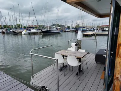 a wooden deck with a table and chairs on a boat at Houseboat De Amstel in Monnickendam