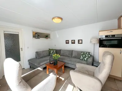 a living room with couches and a table at Gelijkvloers Vakantieappartement 150m van Strand Egmond aan Zee in Egmond aan Zee