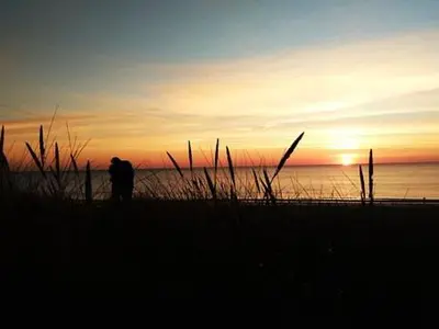 a person walking on the beach at sunset at Gelijkvloers Vakantieappartement 150m van Strand Egmond aan Zee in Egmond aan Zee