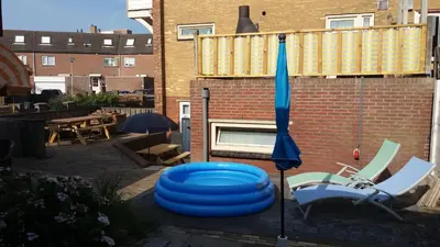 a blue frisbee and two chairs and an umbrella at Gelijkvloers Vakantieappartement 150m van Strand Egmond aan Zee in Egmond aan Zee