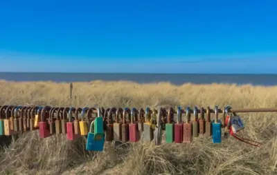 a row of locks on a fence in a field at Gelijkvloers Vakantieappartement 150m van Strand Egmond aan Zee in Egmond aan Zee