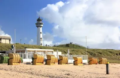a lighthouse with a bunch of chairs on the beach at Studio aan Zee op 150 Meter van Strand in Egmond aan Zee