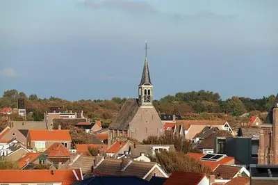 a church with a steeple on top of a city at Studio aan Zee op 150 Meter van Strand in Egmond aan Zee