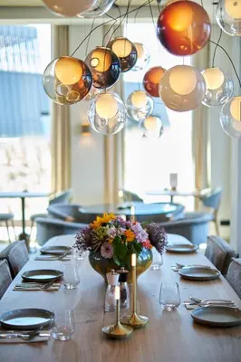 a table with a vase of flowers and lights at Boutique Hotel Blendin Bloemendaal aan Zee in Bloemendaal Aan Zee