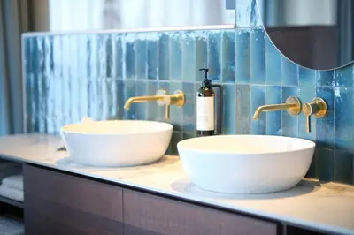 a bathroom with two white sinks and a bottle of soap at Boutique Hotel Blendin Bloemendaal aan Zee in Bloemendaal Aan Zee