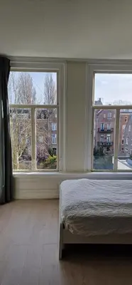 a bedroom with a bed and two large windows at Frank’s and Chong’s excellent location in Amsterdam