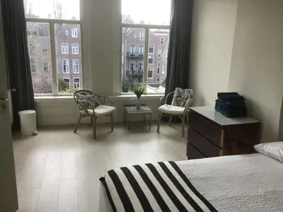 a bedroom with a bed and two chairs and windows at Frank’s and Chong’s excellent location in Amsterdam