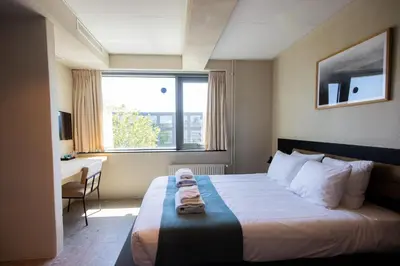 a hotel room with a bed and a desk and a window at Rooms25 in Amsterdam