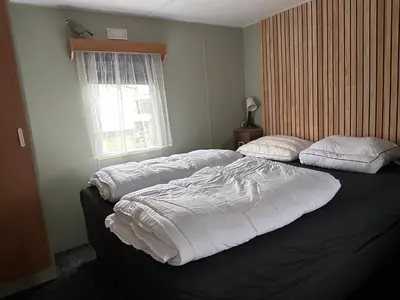 a bedroom with two beds with white sheets and a window at Retro Stacaravans in Warmond