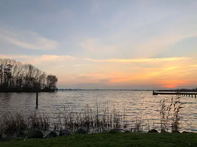 a view of a lake at sunset with a dock at Retro Stacaravans in Warmond