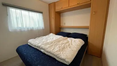 a bed in a small room with a window at Retro Stacaravans in Warmond